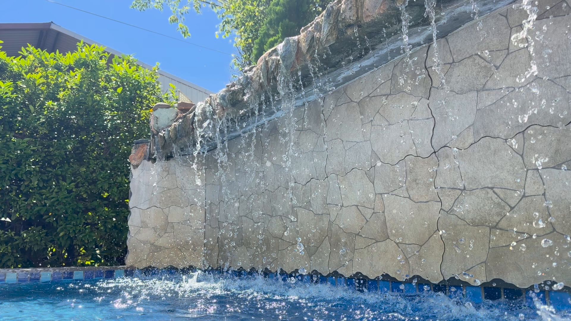 Haven's private pool and stone waterfall in a walled garden, Belize City