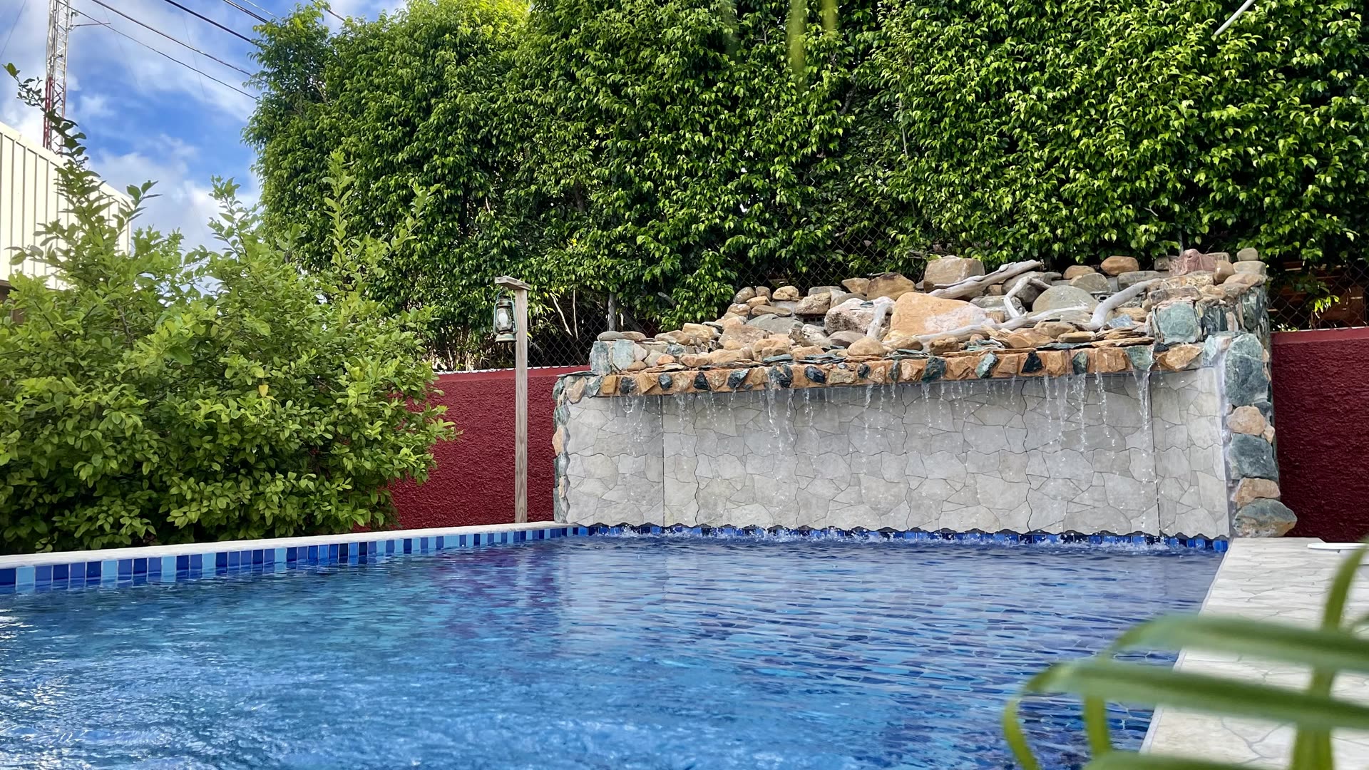 Haven's private pool and stone waterfall in a walled garden, Belize City